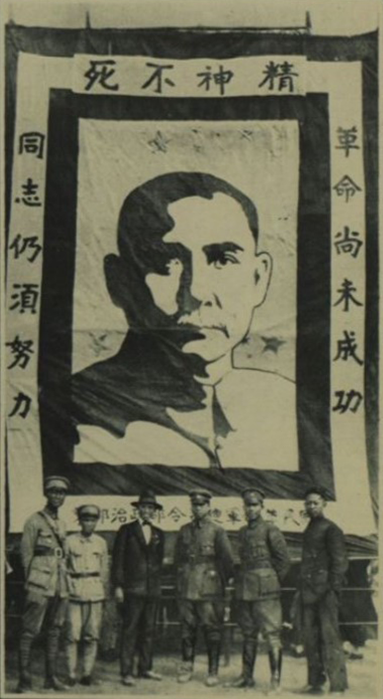 >附有孫中山晚年肖像的大型海報於廣東九江的軍營展示，一衆軍官在海報前方合影。